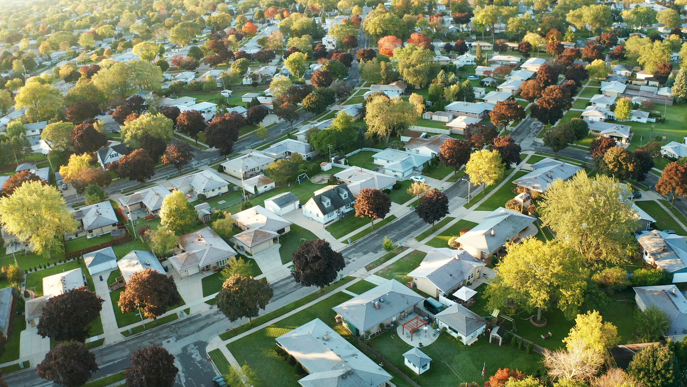 Aerial view of a suburban neighborhood with single-family homes, streets, and mature trees.