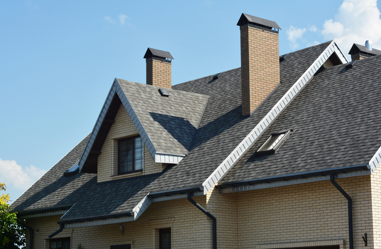 Asphalt shingle roof on a residential home with multiple rooflines and chimneys